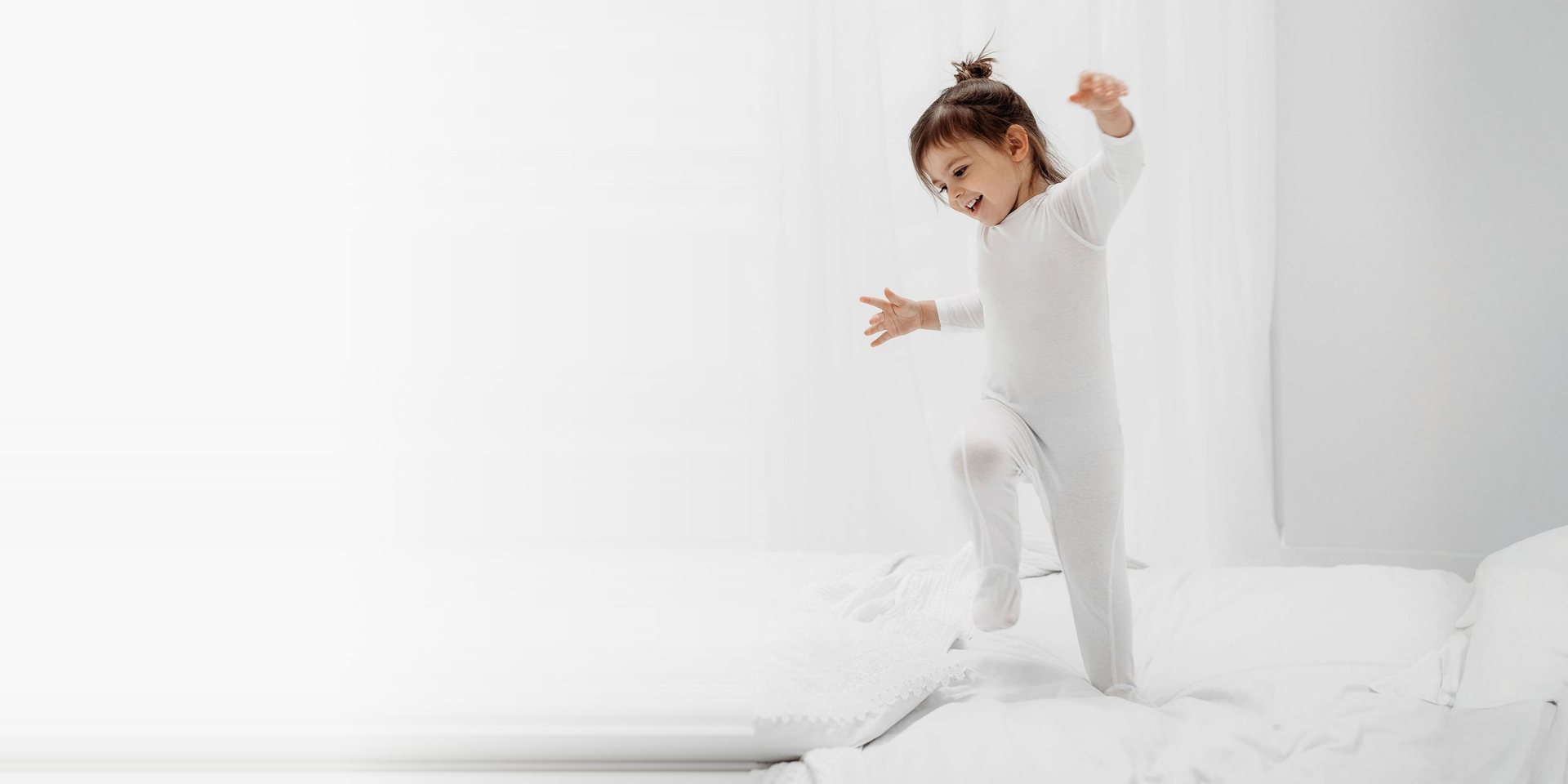 Child in HappySkin base layers jumping on a bed