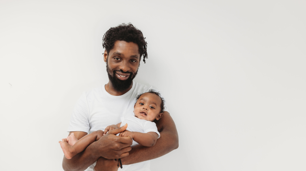happy father holds his baby in a white eczema bodysuit