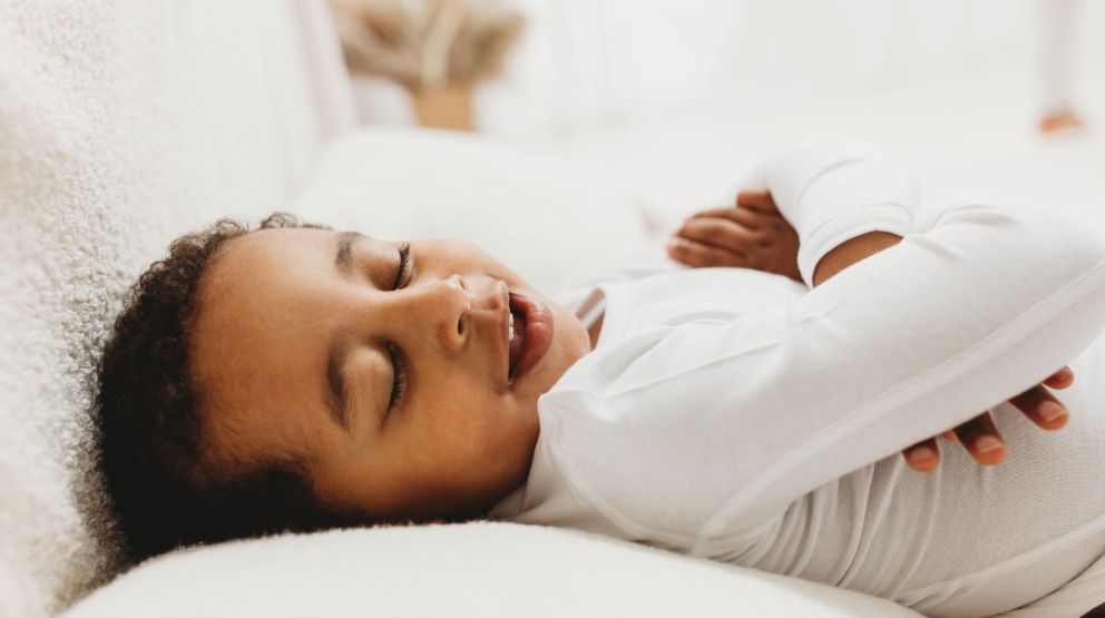 Young child aged 3-6 sleeping peacefully in bed wearing therapeutic eczema wear